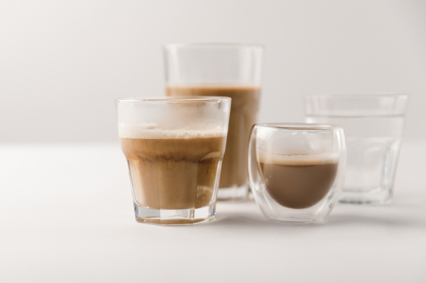 Ποτήρια με καφέ και γάλα σε λευκό φόντο - Φωτογραφία, εικόνα