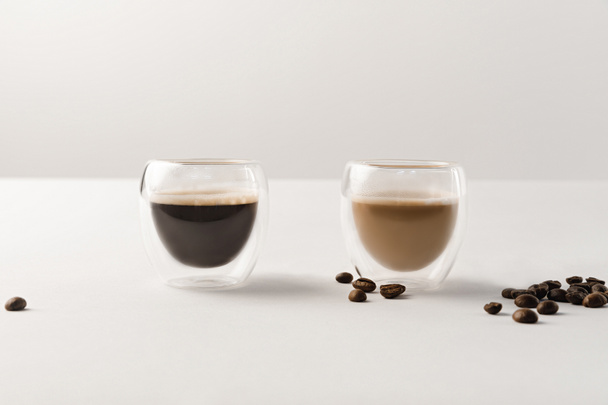 Deux tasses avec café sur fond blanc avec grains de café
 - Photo, image
