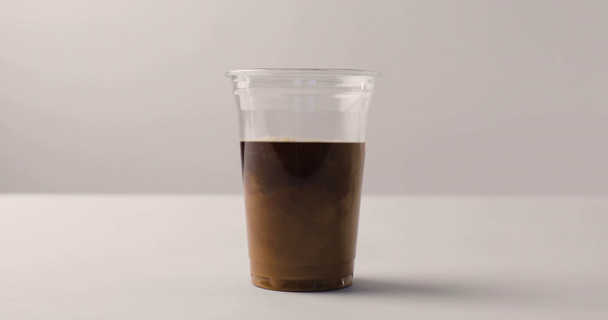 Ρίχνει γάλα σε μαύρο καφέ σε λευκό φόντο - Πλάνα, βίντεο