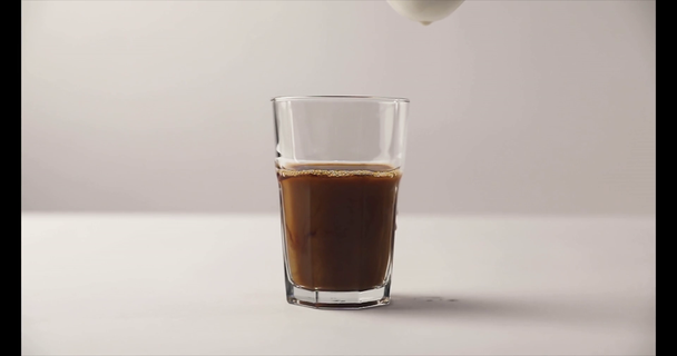 Movimiento lento de verter la leche en el vidrio Old Fashioned con café sobre fondo blanco
 - Imágenes, Vídeo