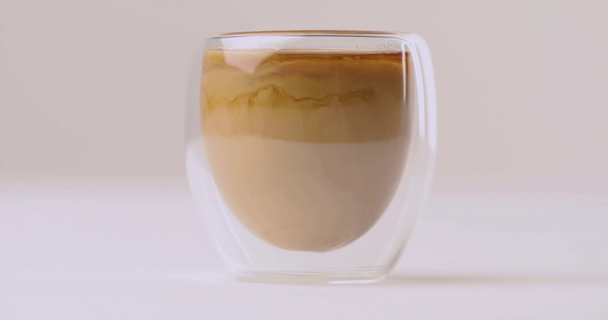 Verter leche en taza con café sobre fondo blanco
 - Metraje, vídeo