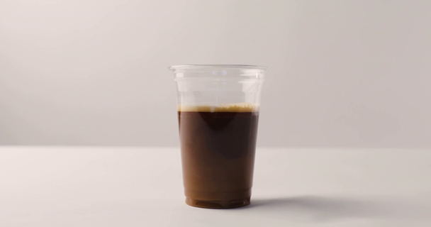 Додавання молока до кави у пластиковій чашці на білому тлі з зворотним кадром
 - Кадри, відео