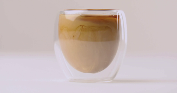 Выливание молока в стакан с черным кофе на белом фоне
 - Кадры, видео