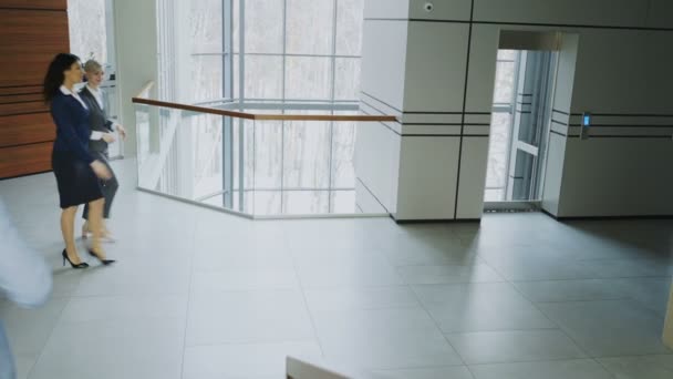 Empresarios y compañeras de trabajo caminan y se reúnen en un moderno centro de oficinas en interiores
 - Metraje, vídeo