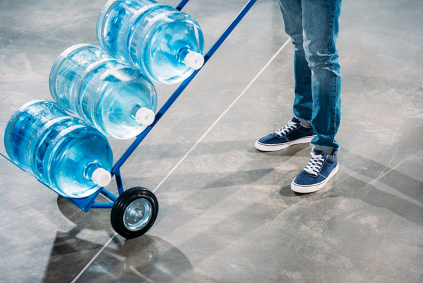 Zbliżenie człowieka loader stoi wóz z butelek po wodzie - Zdjęcie, obraz