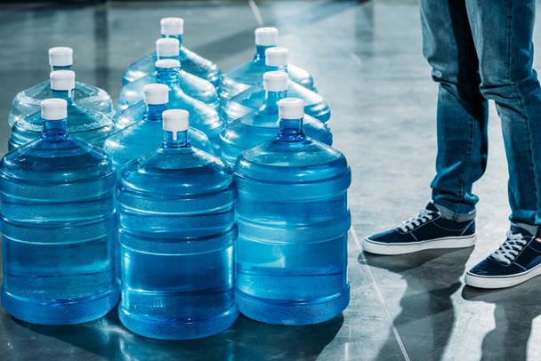 Κούριερ (Courier) στέκεται από μεγάλα μπουκάλια με πόσιμο νερό - Φωτογραφία, εικόνα