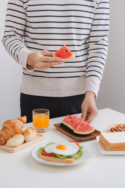 άνθρωπος τρώει πρωινό στο σπίτι, πρωί με σάντουιτς και φρούτα. - Φωτογραφία, εικόνα