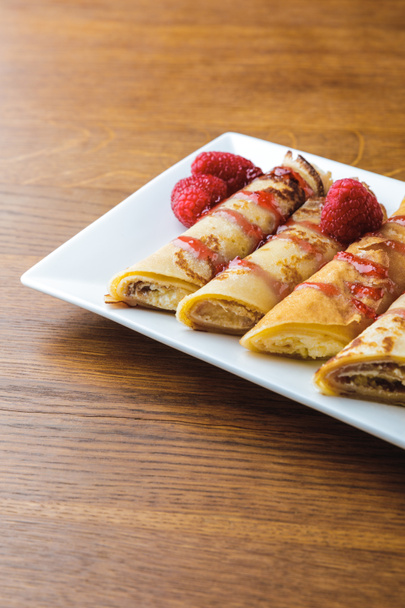delicious sweet rolled pancakes with raspberries and jam  - Foto, afbeelding