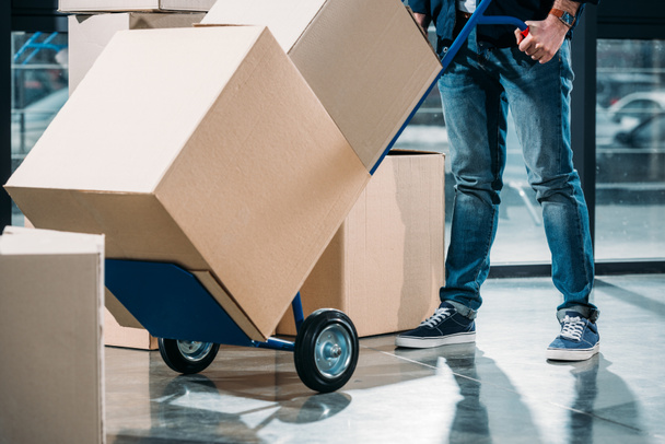 Close-up view of delivery man carrying boxes on cart - Photo, image