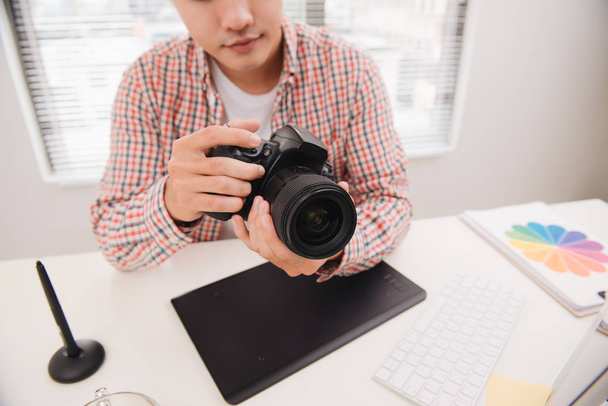 Fotógrafo masculino, sentado em sua mesa, olhando para a câmera
 - Foto, Imagem