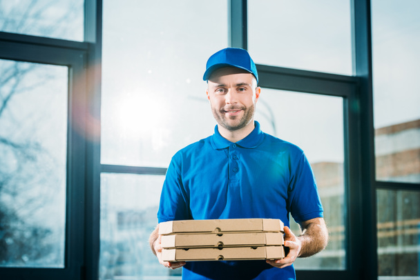 Smiling delivery man carrying pizzas in boxes  - 写真・画像
