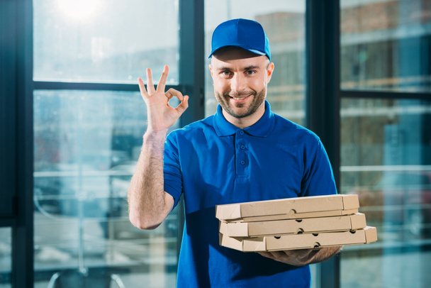 Smiling courier with pizzas in boxes showing ok sign - Photo, image
