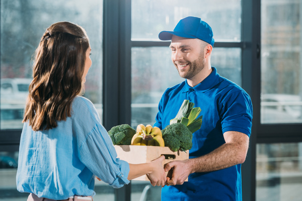 Courier giving woman box with fresh fruits and vegetables - Foto, imagen