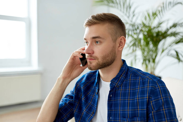 smiling young man calling on smartphone at office - Photo, Image