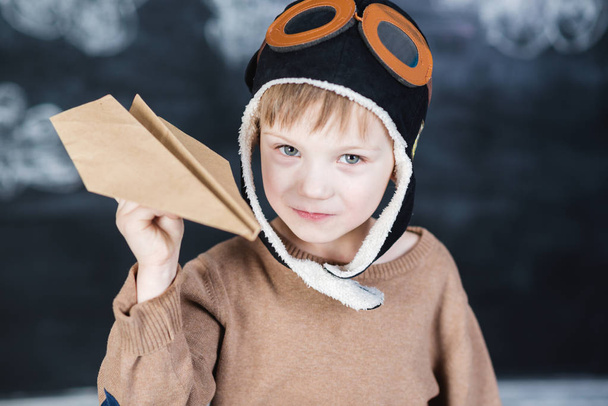 the boy in the pilot's cap plays a paper plane - Foto, Bild