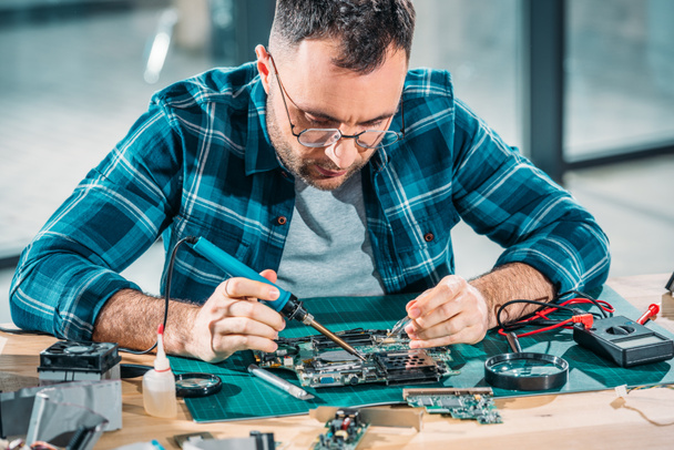 Hardware engineer in glasses soldering pc parts - Photo, Image