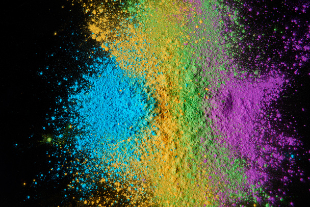 top view of colorful holi powder isolated on black, Hindu spring festival - Фото, изображение
