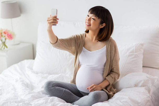 pregnant woman taking selfie by smartphone at home - Fotografie, Obrázek