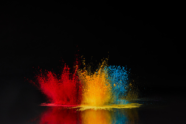 explosión de polvo de holi rojo, azul y amarillo en negro, festival hindú de primavera
 - Foto, Imagen