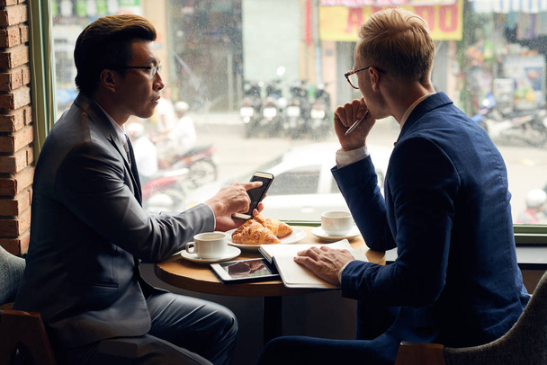 Kahvaltı ve yeni fikirler iş için tartışırken iş adamları - Fotoğraf, Görsel
