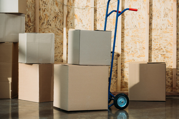 Cardboard packages and delivery cart in warehouse room - Photo, Image