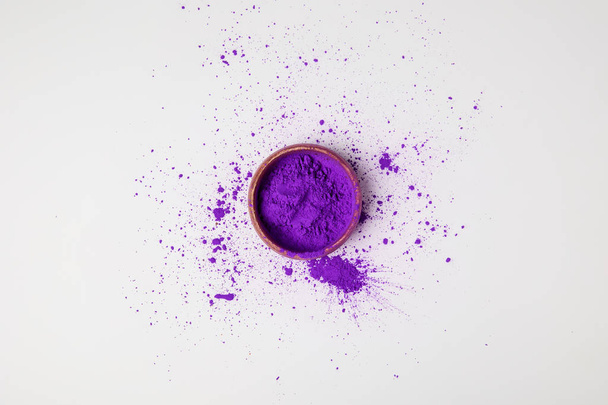 vista superior de la pintura holi púrpura en cuenco aislado en blanco, festival de colores
 - Foto, Imagen