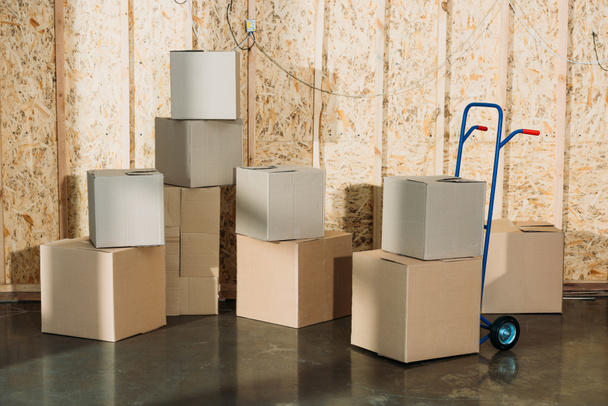 Cardboard boxes and hand truck in warehouse room - Photo, Image