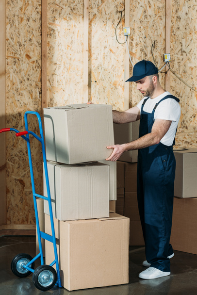 Loader man stacking cardboard boxes on cart - Фото, изображение