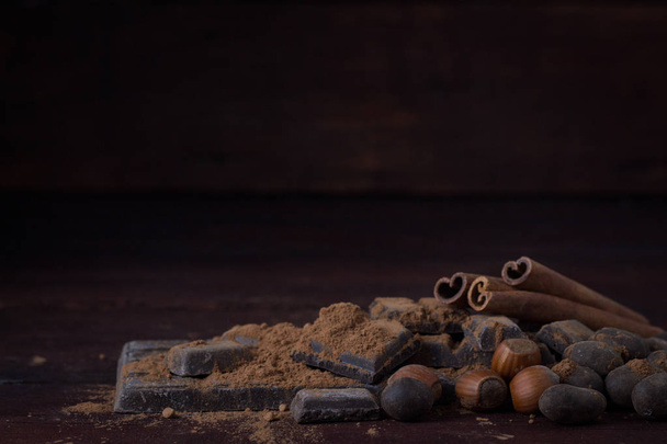 Schokolade, Gewürze, Löffel mit Kakao, Zimt, Nüsse auf dunklem Holz - Foto, Bild