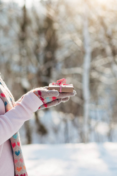 Young girl holds gift in hands in winter park - Photo, Image
