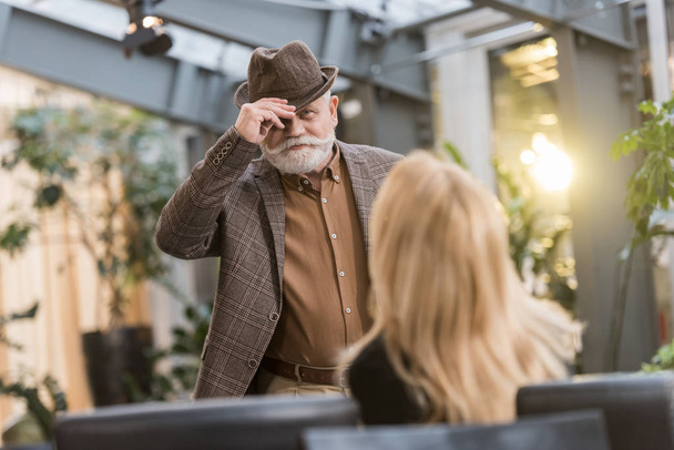 selective focus of senior man in hat looking at woman at table in cafe - Foto, Imagem