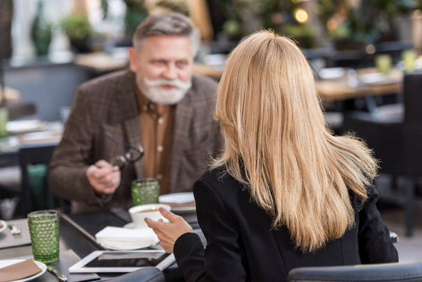 selective focus of businessman and businesswoman having meeting in cafe - Photo, image