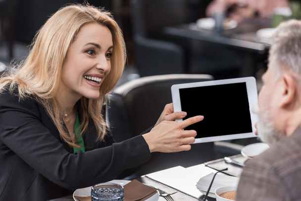 vista lateral de la mujer de negocios con la tableta durante la reunión con su colega en la cafetería
 - Foto, imagen