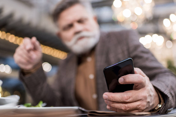 selective focus of businessman using smartphone in cafe - Foto, imagen