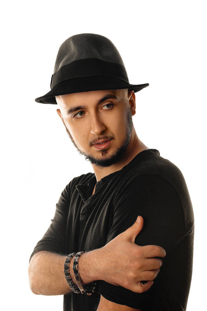 portrait of young unshaved man in hat wearing black and looking  - Foto, imagen