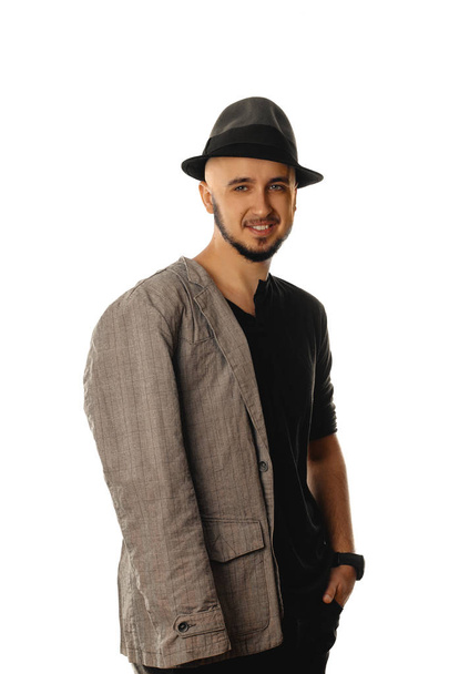Happy young unshaved man in hat and jacket smiling on camera  - Foto, afbeelding