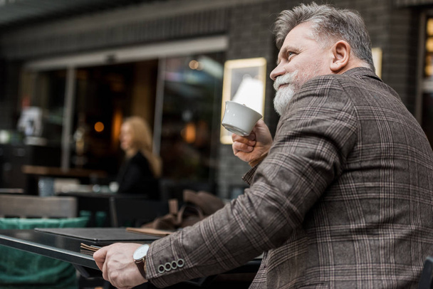 Μερική άποψη του ανώτερος άνθρωπος με φλιτζάνι καφέ στην καφετέρια - Φωτογραφία, εικόνα