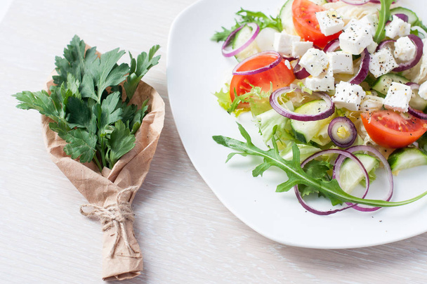 新鮮な春サラダ キュウリ、トマト、チーズ、ルッコラ軽い木製の背景の白いプレートに分離 - 写真・画像