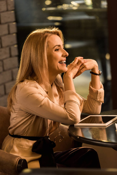 boční pohled usměvavá podnikatelka sedí u stolu s tabletem - Fotografie, Obrázek