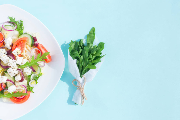 Čerstvý jarní salát s okurkou, rajčaty, sýr a rukolou izolované na bílém štítku na modrém pozadí - Fotografie, Obrázek