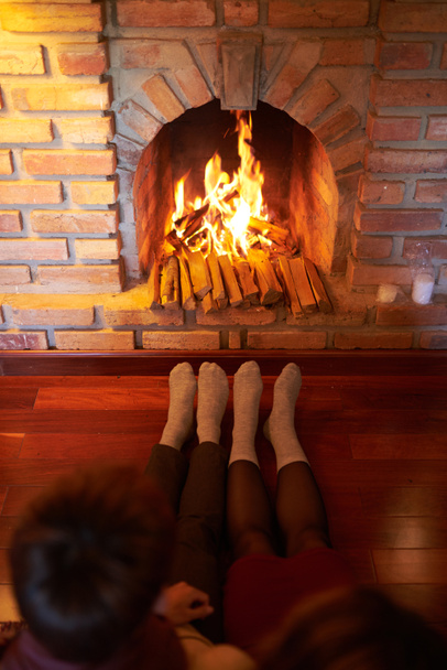 Couple en chaussettes réchauffement des pieds à la cheminée dans le salon
 - Photo, image