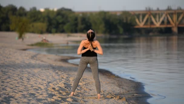 Menina bonita envolvida em ioga na praia na primavera
 - Filmagem, Vídeo