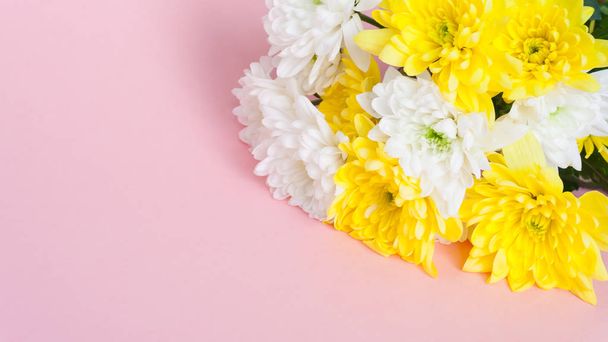 bouquet of white and yellow chrysanthemums on a pale pink background - 写真・画像