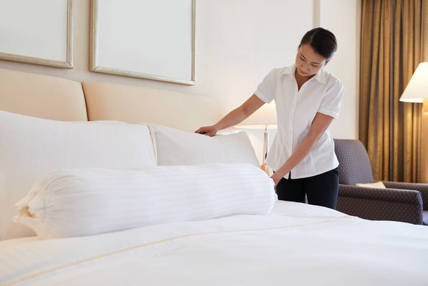 Βιετναμέζικα-νεαρή γυναίκα, κάνοντας το κρεβάτι στο δωμάτιο του ξενοδοχείου - Φωτογραφία, εικόνα