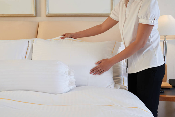Meid schikken kussens op het bed - Foto, afbeelding