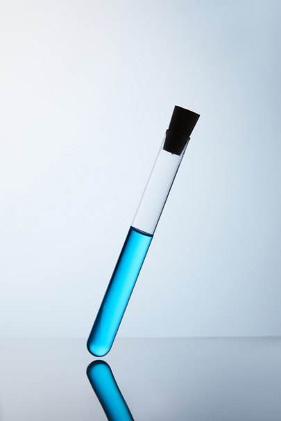 tubo químico lleno de líquido azul en la superficie reflectante
 - Foto, Imagen