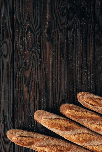 κάτοψη του τοποθετημένα loafs από Γαλλική μπαγκέτα σε ξύλινη επιφάνεια - Φωτογραφία, εικόνα