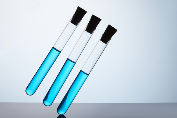row of test tubes filled with blue liquid on grey - Foto, imagen