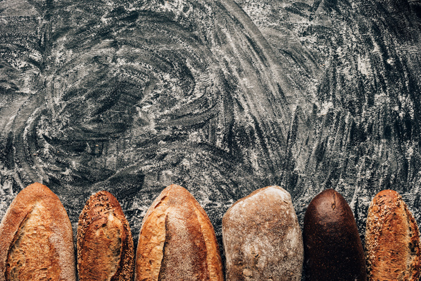 vista dall'alto di pagnotte disposte di pane su tavolo scuro con farina
 - Foto, immagini