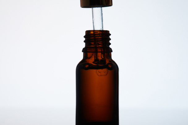 close-up shot of bottle of aromatic oil with pipette on white - Фото, изображение